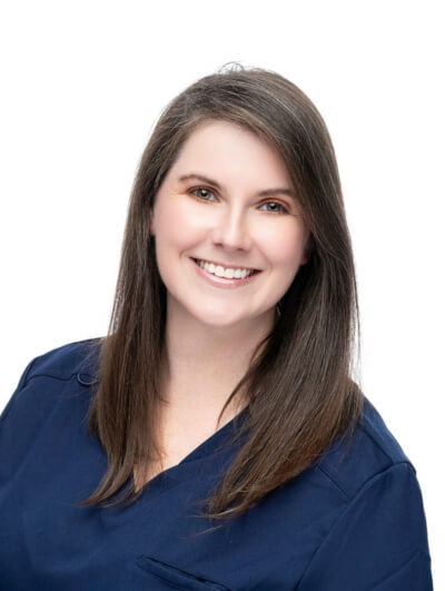 A woman with straight, shoulder-length brown hair is smiling and wearing a navy blue top, posed against a plain white background.